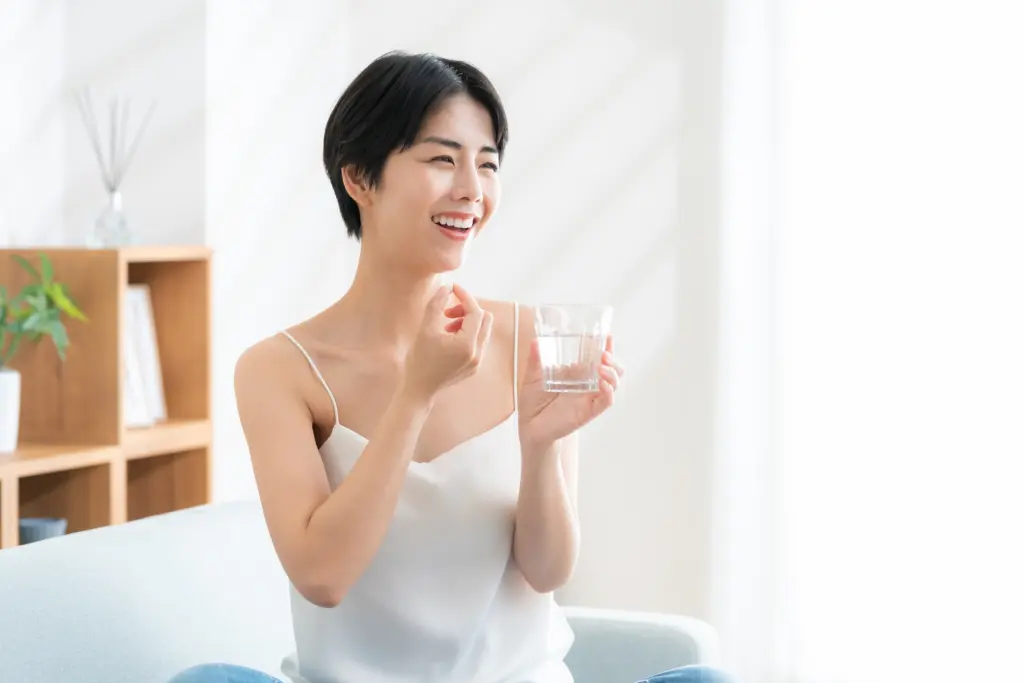 リビングでサプリを飲む若い女性
