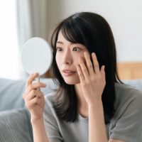 鏡で肌を見る女性