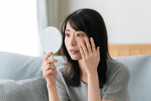 鏡で肌を見る女性