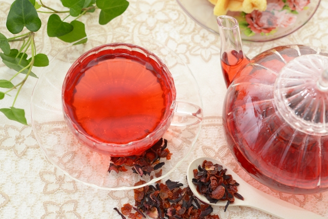 ガラスのカップとティーポットに注がれた赤いローズヒップティーと乾燥ローズヒップ。抗酸化作用やビタミンCが注目される人気のハーブティー。