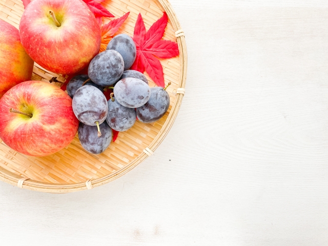 植物性食品に含まれる天然成分を象徴するような、りんごとブルーベリーが入った明るい籠の写真。ナチュラルな木製テーブルと紅葉が添えられた静かな構図は、抗栄養因子と健康への影響に関するコラムにやさしく彩りを添える。