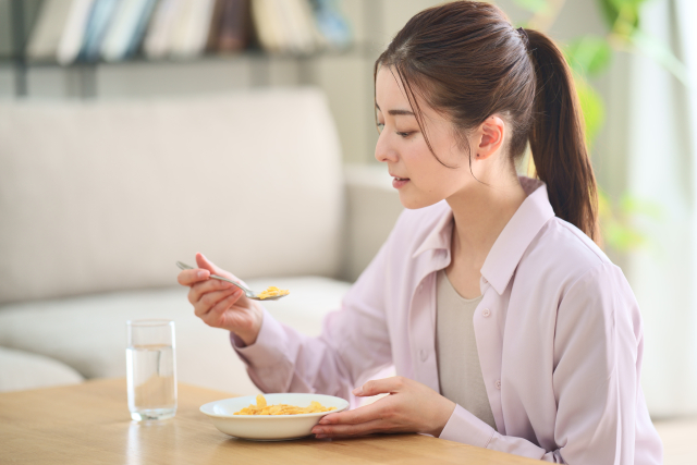 現代的な日本人女性がスプーンでシリアルを口元に運ぶ瞬間。整った顎のラインと顔立ちが特徴的で、咀嚼や食生活と顔貌の関係を考察する記事文脈に合致した視覚的要素。