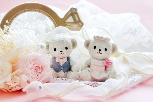 夫婦のように寄り添う二匹のくまのぬいぐるみと、レースやバラの可愛らしい装飾。パートナーシップと心のつながりを象徴する癒し系のイメージで、食事と人間関係の関係性をやさしく表現。