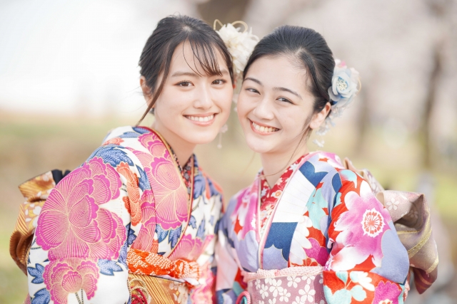 和装の若い女性二人が微笑みながら顔を寄せ合う様子。食生活や栄養状態が顔貌に与える影響を探るコラムの文脈に関連し、若年女性の顔立ちの多様性と健康美を象徴するイメージ。