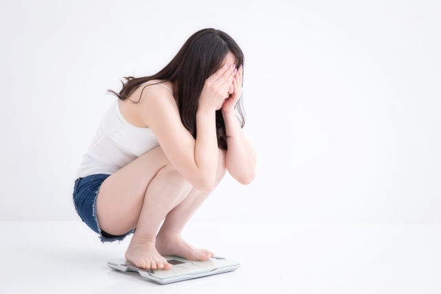 体重計に乗り残念がる女性