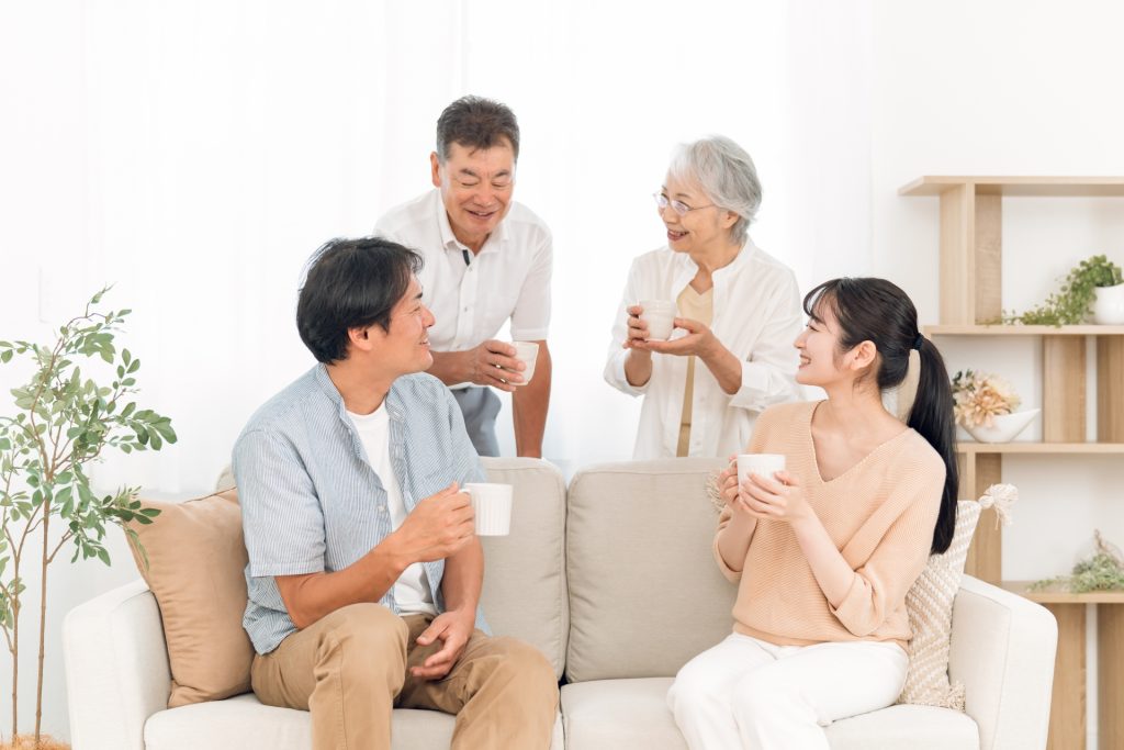 ソファに座って飲み物を飲む家族(話す)