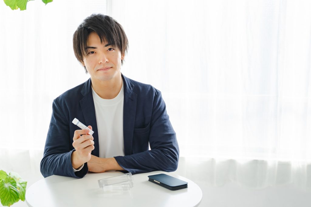 
検査キットの容器を持つ男性