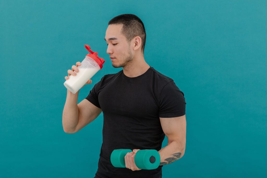 
プロテインを飲みながらダンベル運動する男性