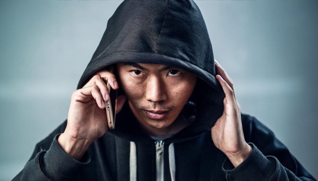 
電話するフードを被った怪しい人物。防犯