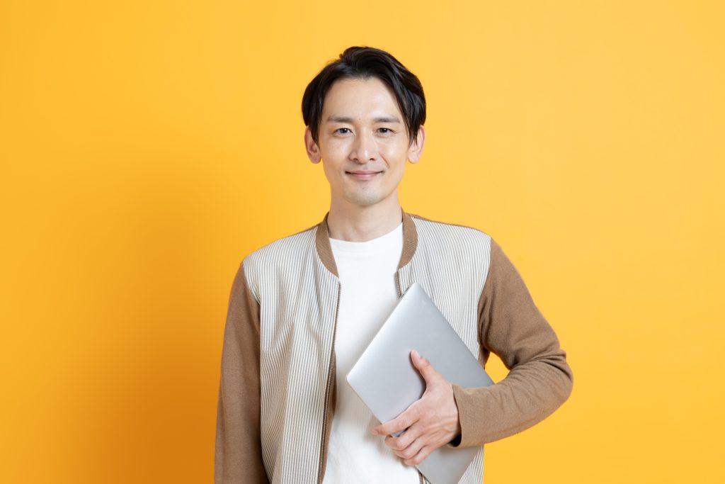 
パソコンを持つ笑顔の日本人男性