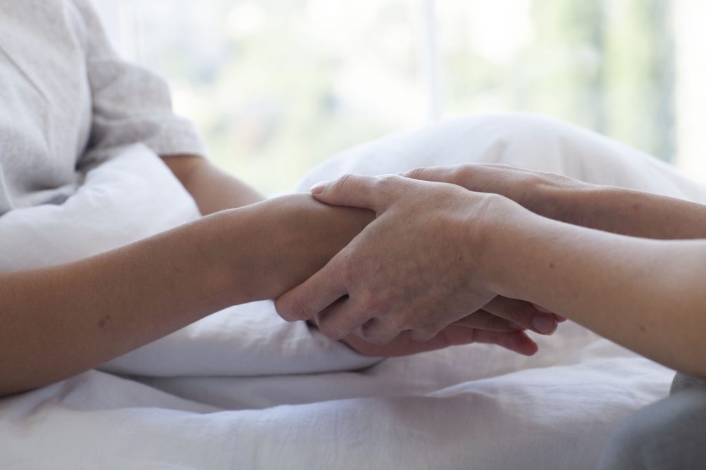 入院している女性の手を握る
