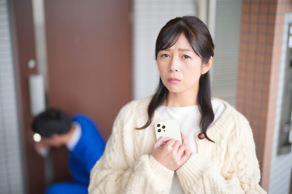 玄関の鍵穴を見ている男性と不安そうな女性