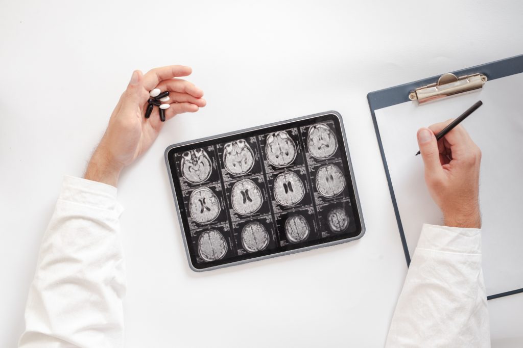 薬を持ってバインダーに書いている医師のデスク