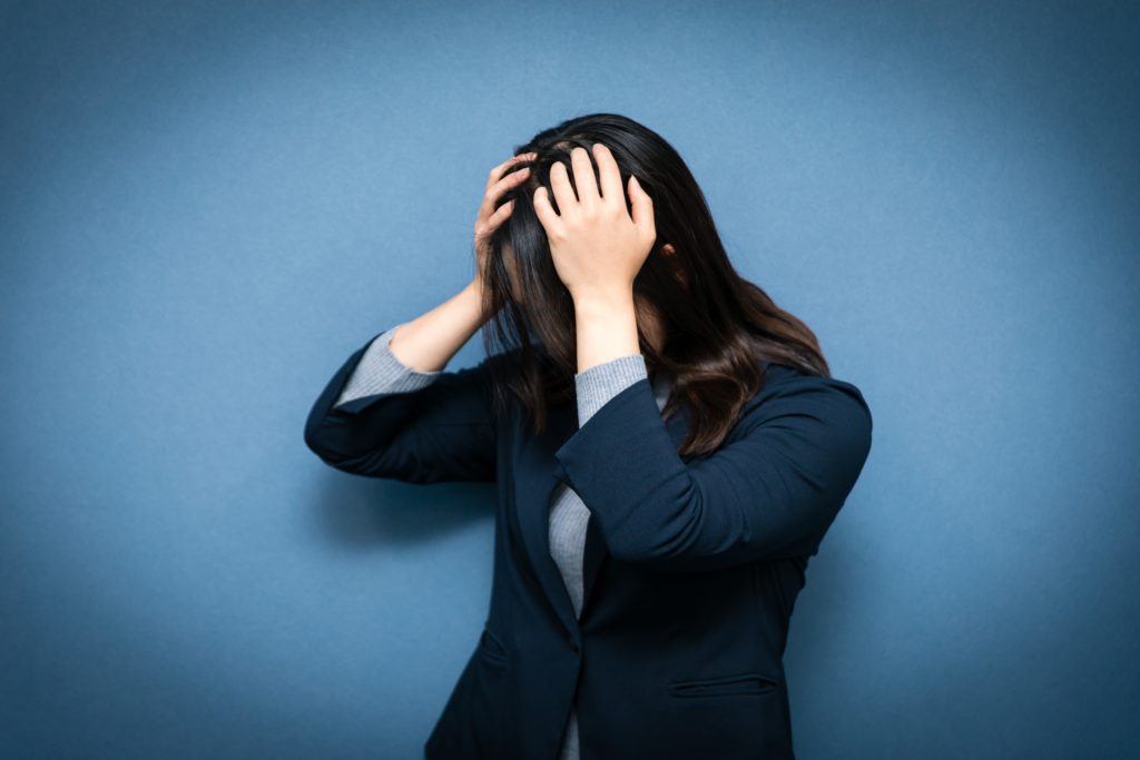 スーツを着た女性が頭を抱える