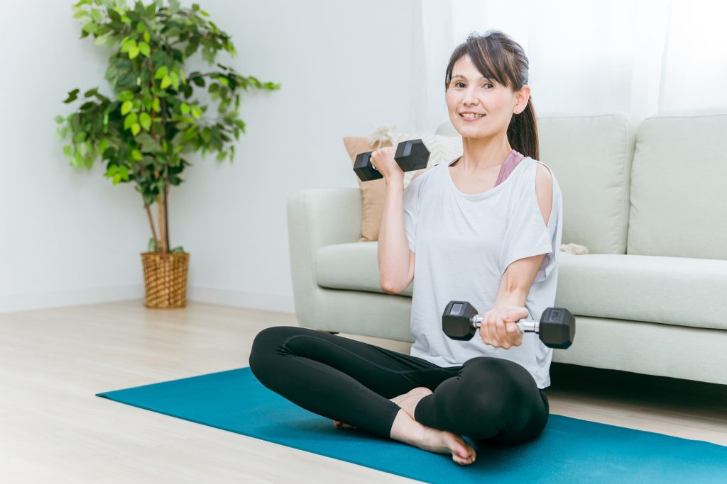 
部屋で筋トレをする中高年女性