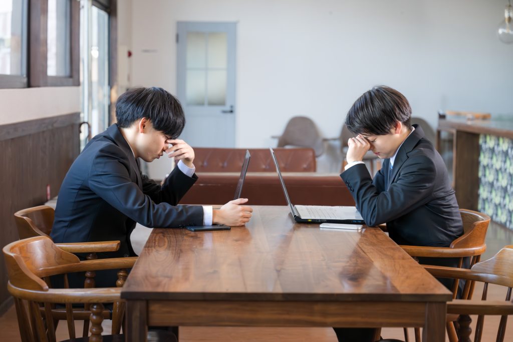 
スマホと働く頭を抱えるビジネスマン達