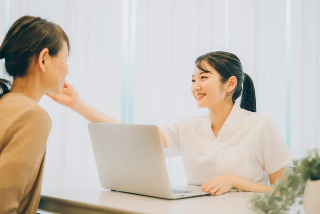 カウンセリングする白衣を着た女性(肌チェック