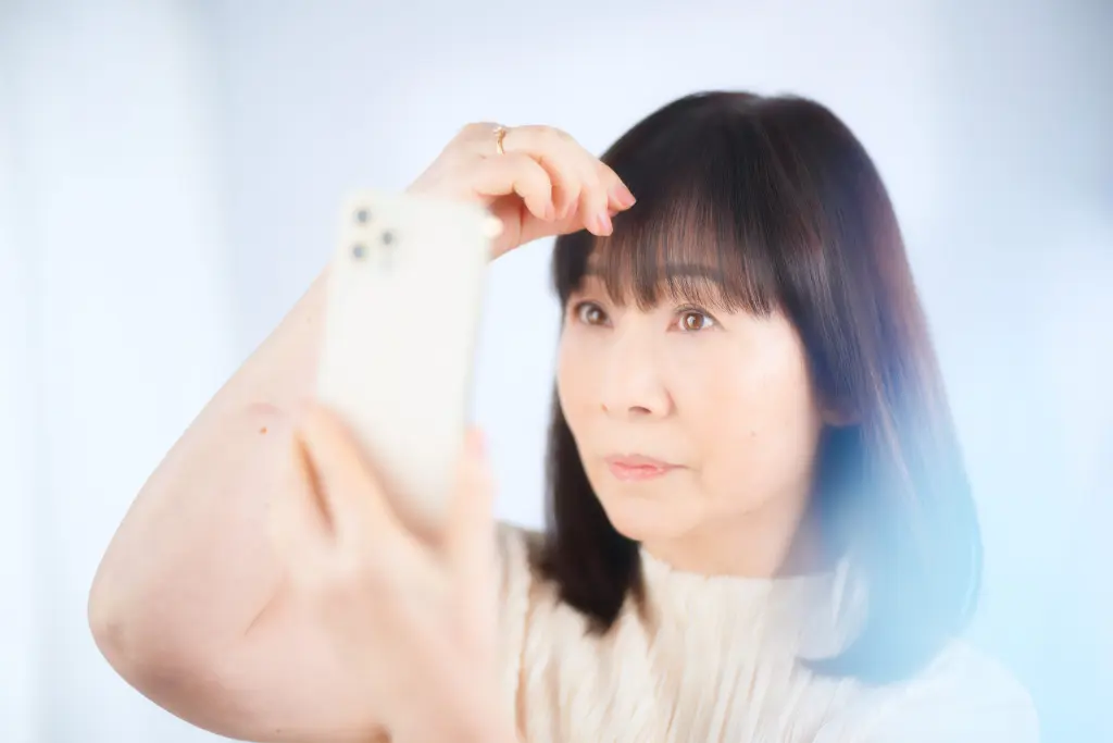 スマートフォンを鏡代わりにしている女性