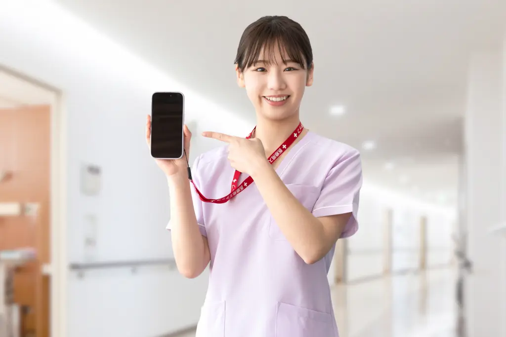 スマホを指差す笑顔の女性医療スタッフ