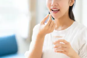リビングでサプリを飲む若い女性