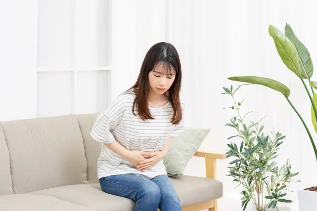 お腹をおさえる　女性