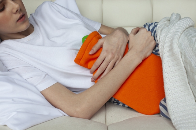 ゆたんぽでお腹を温める女性