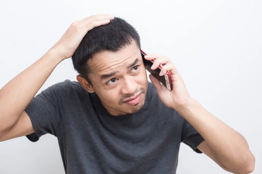 植毛の仕上がりに不安を感じ、頭に手をあてて悩む男性