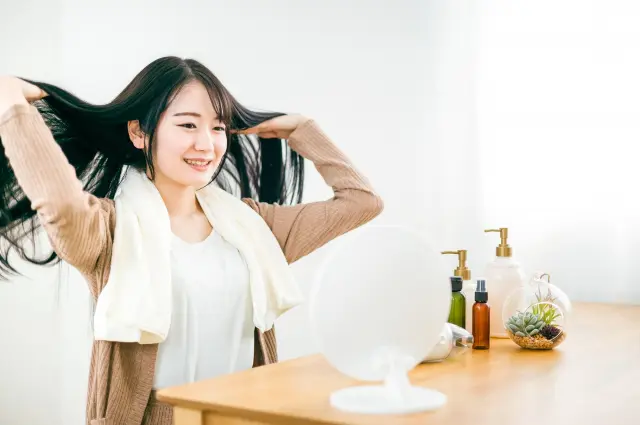 鏡の前で髪の状態を確認する女性