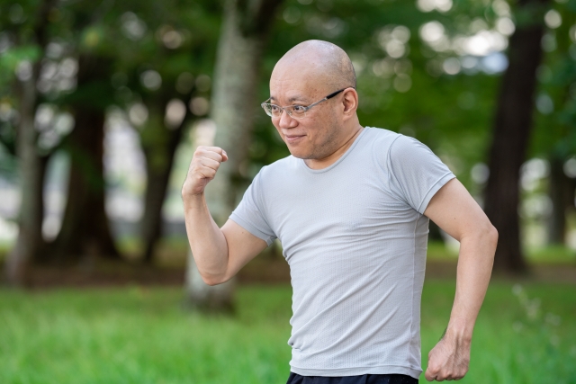 公園で運動する中年のスキンヘッド男性。髪の薄さとややふっくらとした体型が相まって、実年齢よりやや老けた印象を与える外見の一例。
