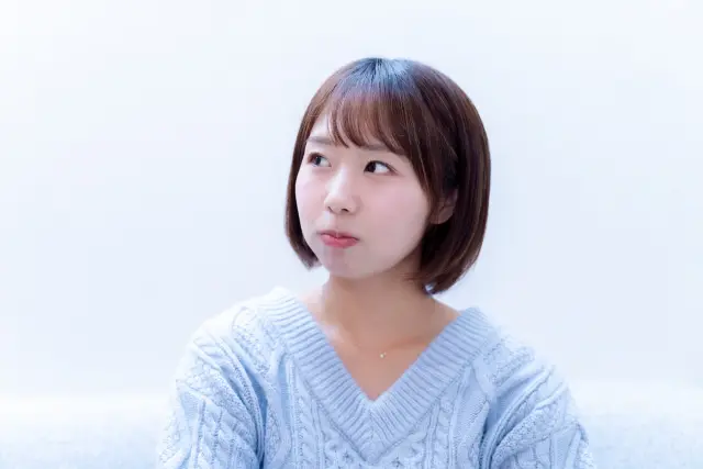 ふくれっ面で視線をそらす若い女性のイメージ|外見への不満や美容に対する迷いや戸惑いを象徴する表情