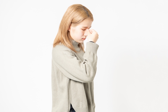 目を閉じてうつむき、鼻の付け根をつまむ右手に思い悩む感情がにじむ若い女性の姿。期待が裏切られ、深い落胆に包まれる様子が印象的。外見の変化に対する高すぎた期待や、理想と現実のギャップを象徴するイメージ。