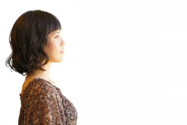 横顔の女性。ショートヘアにパーマをかけた髪型が特徴的で、髪型が大人びた印象や見た目年齢に与える影響を象徴するシーン。