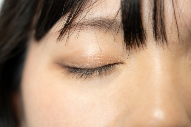 PRP治療後の美しい毛髪の成長を象徴するイメージとして、女性の顔の角をクローズアップ。黒い髪がまるでカラスの羽のように顔を囲み、閉じた瞼には長いまつげが飾られている様子。PRP治療による健康的な髪の状態が伝わる一瞬です。