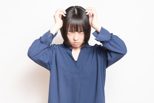 自毛植毛前に頭頂部の痛みや感覚への不安を感じ、目を閉じて頭に触れる女性のイメージ写真