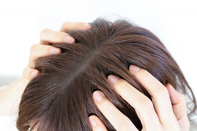 こめかみに置かれた両手が、指先で髪をかき分けながら頭皮に触れている様子。頭皮は繊細かつ複雑な環境であり、植毛治療の前後を通じて丁寧なケアと十分な配慮が必要であることを象徴するイメージ。