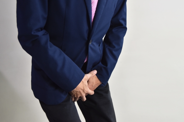 スーツ姿の男性が下腹部を押さえ、強い痛みに顔をゆがめながら前かがみに。前立腺がんと診断されたが、その原因がまさか薄毛治療薬だったとは――頭髪と前立腺、無関係に思えるこのふたつの領域に、思いがけない関連があるのかもしれません。