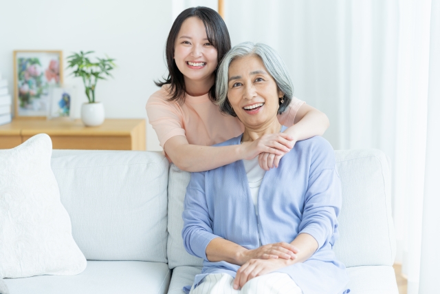 黒髪の女性がグレーヘアの祖母の肩に腕を回して笑顔でポーズ｜家族写真・世代別ヘアスタイルの参考に最適