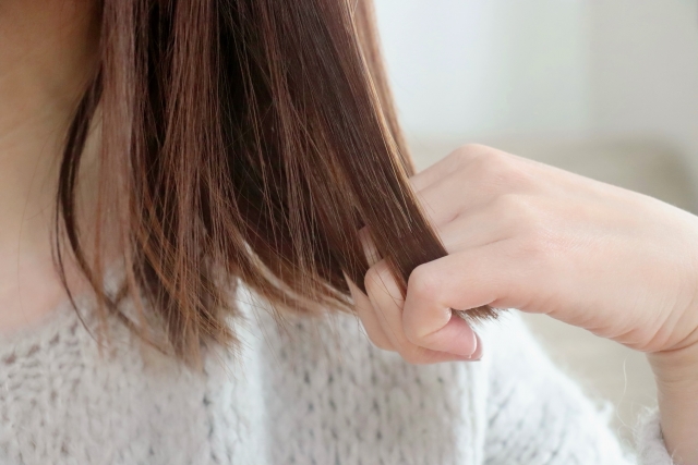 肩までの長さに染めた茶色の髪を手で優しくとかすシーン。髪の毛は滑らかで、細い指がまるで柔らかな櫛のようにすっと通り抜けます。毛髪再生手術後の健康で豊かな髪の質感を表現しています。