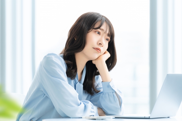 未来に希望を抱く女性が頬杖をつきながら遠くを見つめる姿。艶やかなロングヘアが肩にかかり、上品な横顔を引き立てている。薄毛や抜け毛の悩みを乗り越えたあとの明るい未来を想起させるイメージ。