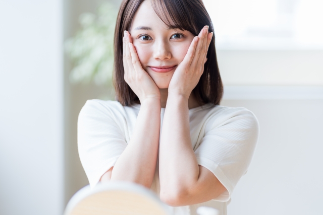 頬に手を添えて笑顔を見せる若い日本人女性｜髪の調子が良い「グッドヘアデー」の理想的な一枚