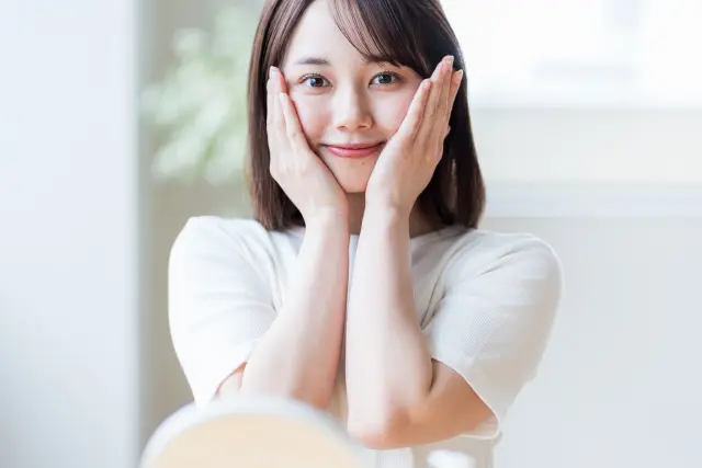 頬に手を添えて笑顔を見せる若い日本人女性|髪の調子が良い「グッドヘアデー」の理想的な一枚