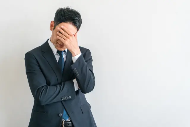 薄毛の不安に悩み、目元を手で覆って深くため息をつく男性のイメージ。脱毛や抜け毛に悩む男性心理やストレスを象徴する場面。