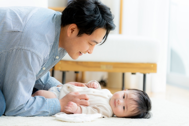 床に敷いたマットの上で、父親が赤ちゃんの息子と楽しそうに遊ぶ姿。遺伝によって受け継がれる特徴が、将来、目に見えるかたちで現れることを示唆する場面。薄毛の傾向も遺伝的に受け継がれる場合があり、望むものも望まないものも受け継ぐのが自然の摂理であることを表現している。