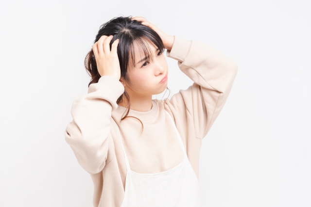 自毛植毛手術を検討する中で、麻酔や痛みに対する不安から頭を抱えて悩む女性のイメージ写真