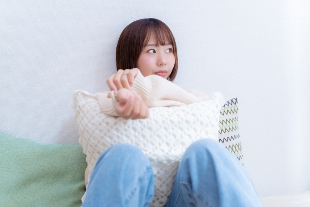 髪の抜け毛や毛周期に不安を感じ、枕を抱えて深く考え込む若い女性のイメージ写真。毛髪の成長メカニズムと再生のしくみを解説する医療系コラム記事に関連