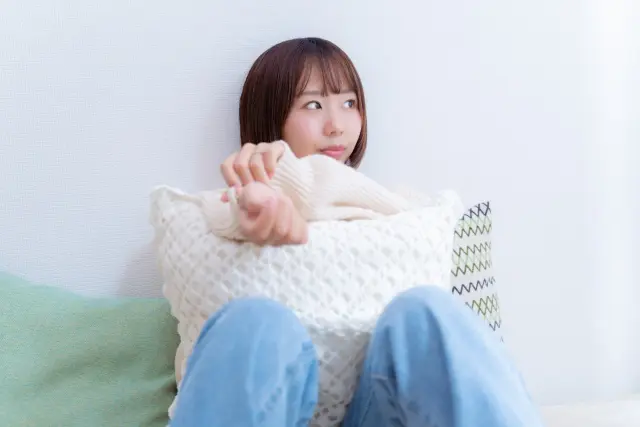 髪の抜け毛や毛周期に不安を感じ、枕を抱えて深く考え込む若い女性のイメージ写真。毛髪の成長メカニズムと再生のしくみを解説する医療系コラム記事に関連