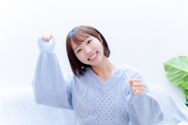 自毛植毛（FUT・FUE）の成功に満足し、喜びの拳を上げる女性。自然な仕上がりに笑顔を見せる、薄毛治療後のポジティブな心境を表現したストックイメージ。