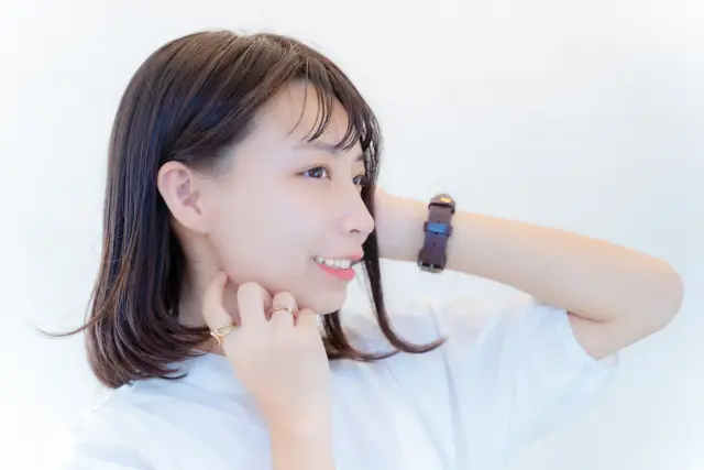 滑らかで艶のある肩までのダークブラウンヘアの女性が横顔で微笑む様子。健康な毛髪の成長やヘアサイクルの正常な状態を象徴するイメージカット。