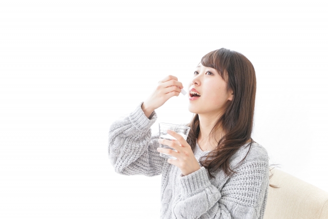 口を開け、手を伸ばして薬を飲もうとしている女性の姿。女性型脱毛症（FPHL）の治療としてスピロノラクトンやフィナステリドなどの内服薬を積極的に取り入れる場面を象徴。薄毛に対する医学的アプローチを前向きに実践する読者像と重なる、治療開始の瞬間を切り取ったイメージ。