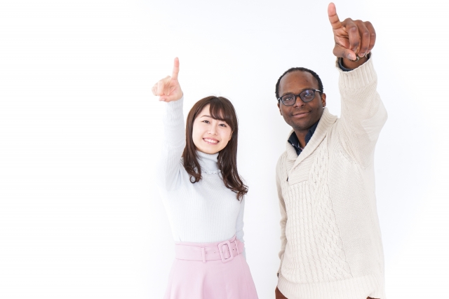 
アフリカ系男性と日本人女性が未来を見据えるように一緒に上を指さしているシーン。自毛植毛の治療方針や仕上がりイメージを共有するポジティブなカウンセリング風景を表現したストック画像。